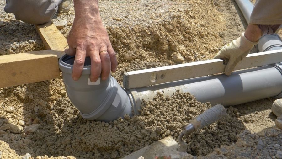 Plumber installing a new underground sewer line with PVC piping during a residential drain and sewer replacement project.