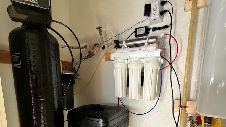 Water softener on wall next to water heater.