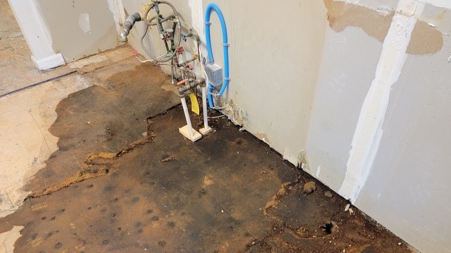 Water-damaged flooring and exposed plumbing caused by a residential slab leak, requiring professional leak detection and plumbing repair.